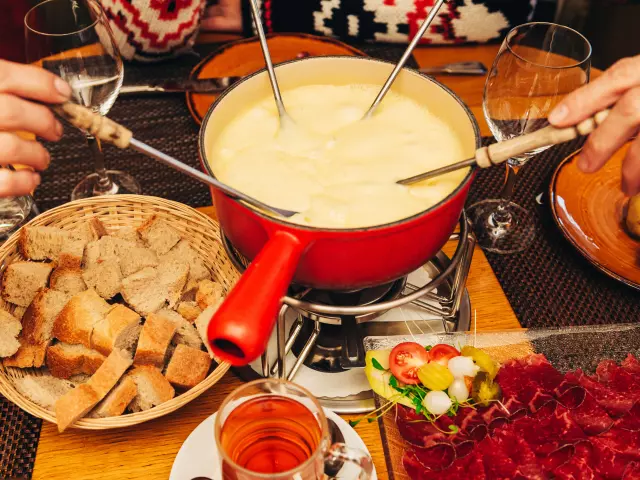 Friends eating cheese fondue in a cozy traditional swiss restaurant 