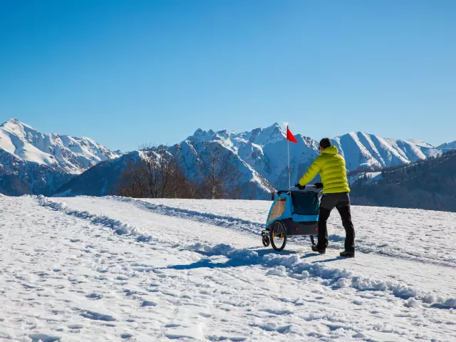 Hiker in the mountains pushing a stroller in the snow