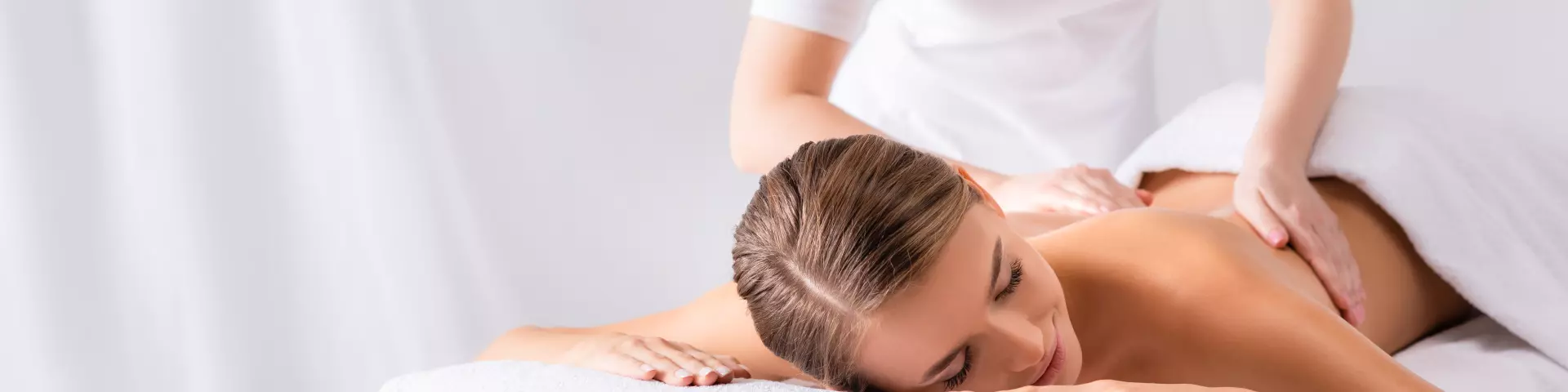 masseur masseert tevreden jonge vrouw op massagetafel in spa salon, banner